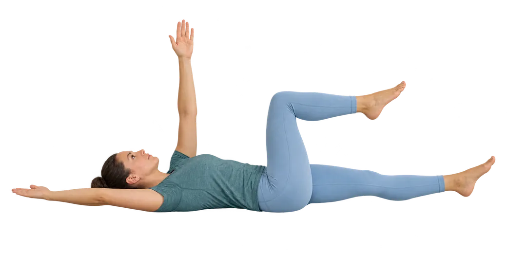 A woman lying on her back doing the dead bug exercise: one arm reaching up, the other arm and one leg extended low, the other knee bent.